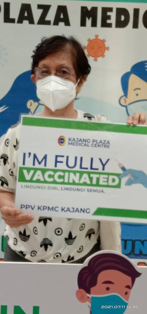 Phang Chee Looi wearing a mask while holding a written placard  I'm Fully Vaccinated