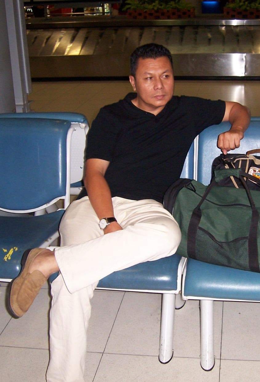Saharuddin Sulaiman, wearing a black shirt and a chino trousers, in a pensive mood sitting with his luggage in a waiting lounge