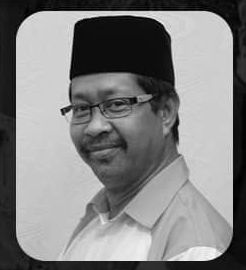 Mohd Sabri Mamat poses in a portrait shot. He is wearing a songkok and a button-down shirt. He has a mustache and rectangular glasses.