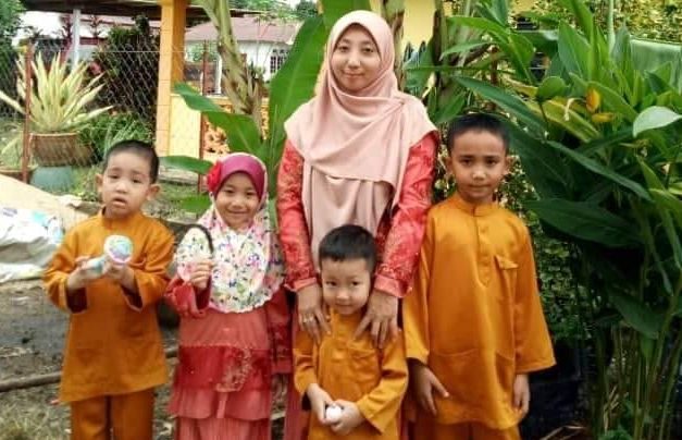 Fatimah Mohd Nawi with her children, a girl and three boys. They are wearing baju kurung and baju melayu.