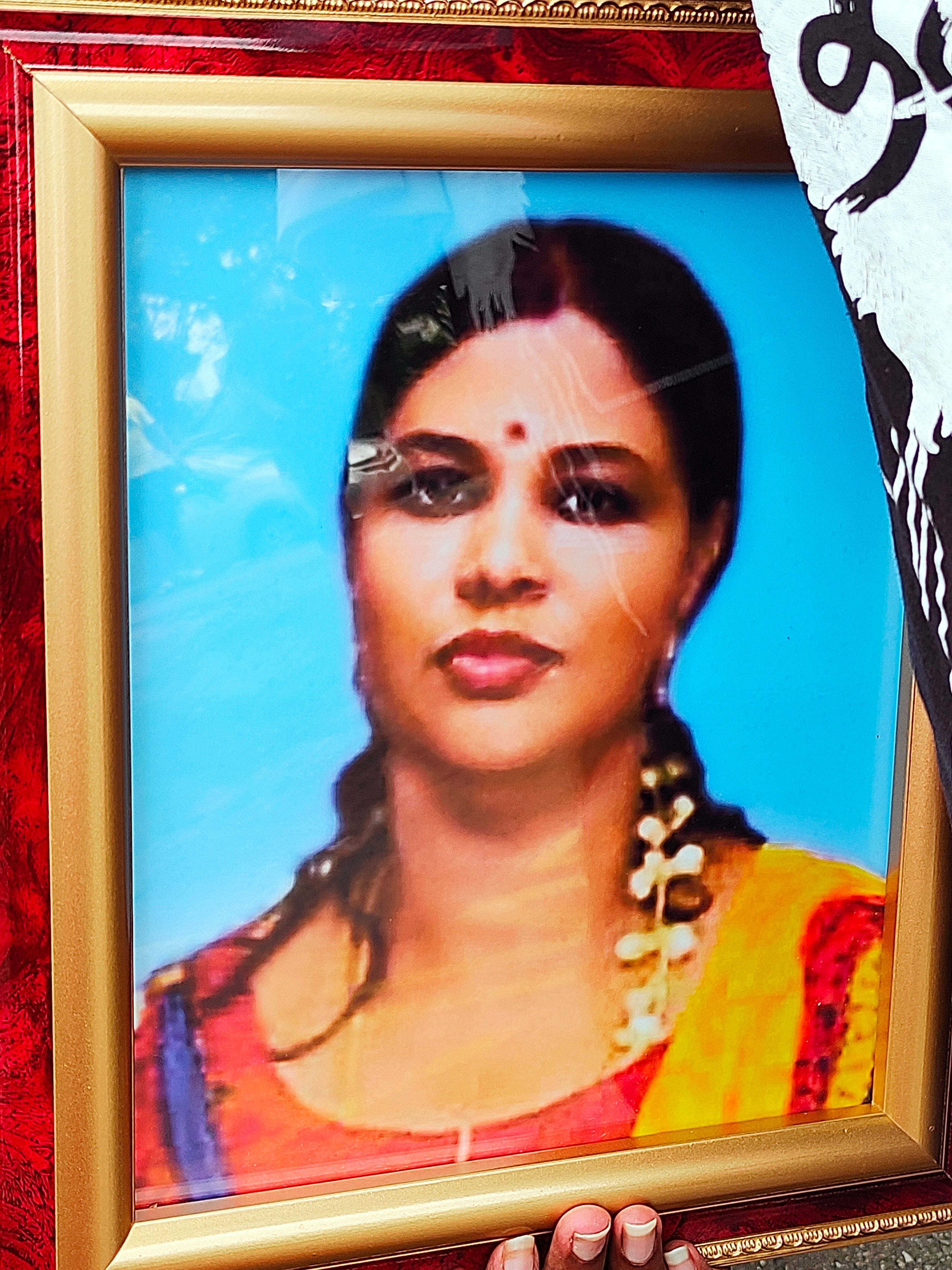 A framed portrait of Citra Subramaniam. She has jasmine flowers in her hair. 