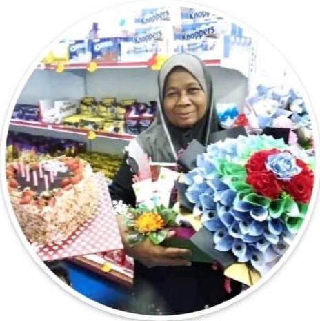 Zainah smiling while holding a bouquet and a cake on her birthday 
