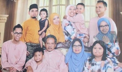 Yahya Arif Ariffin, 68, sits next to his wife and surrounded by their children and grandchildren in a family portrait.