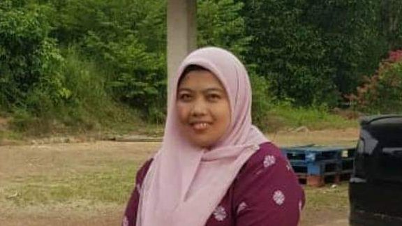 Shuhaiza Mat Isa smiles in a pink headscarf and maroon baju kurung.