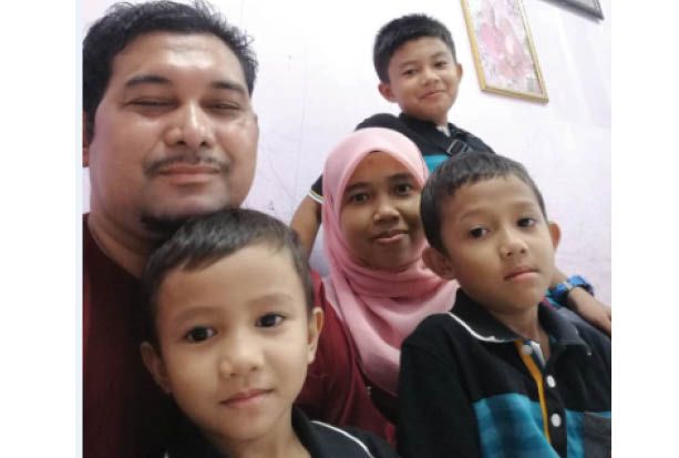 Mohamed Sanizi Hassan, 38, in a wefie with his wife and three boys. One of the boys is in his lap.