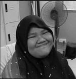 Siti Nur Insyirah Hamzah smiles for the camera. She is wearing a headscarf. Behind her is a stand fan and lockers.